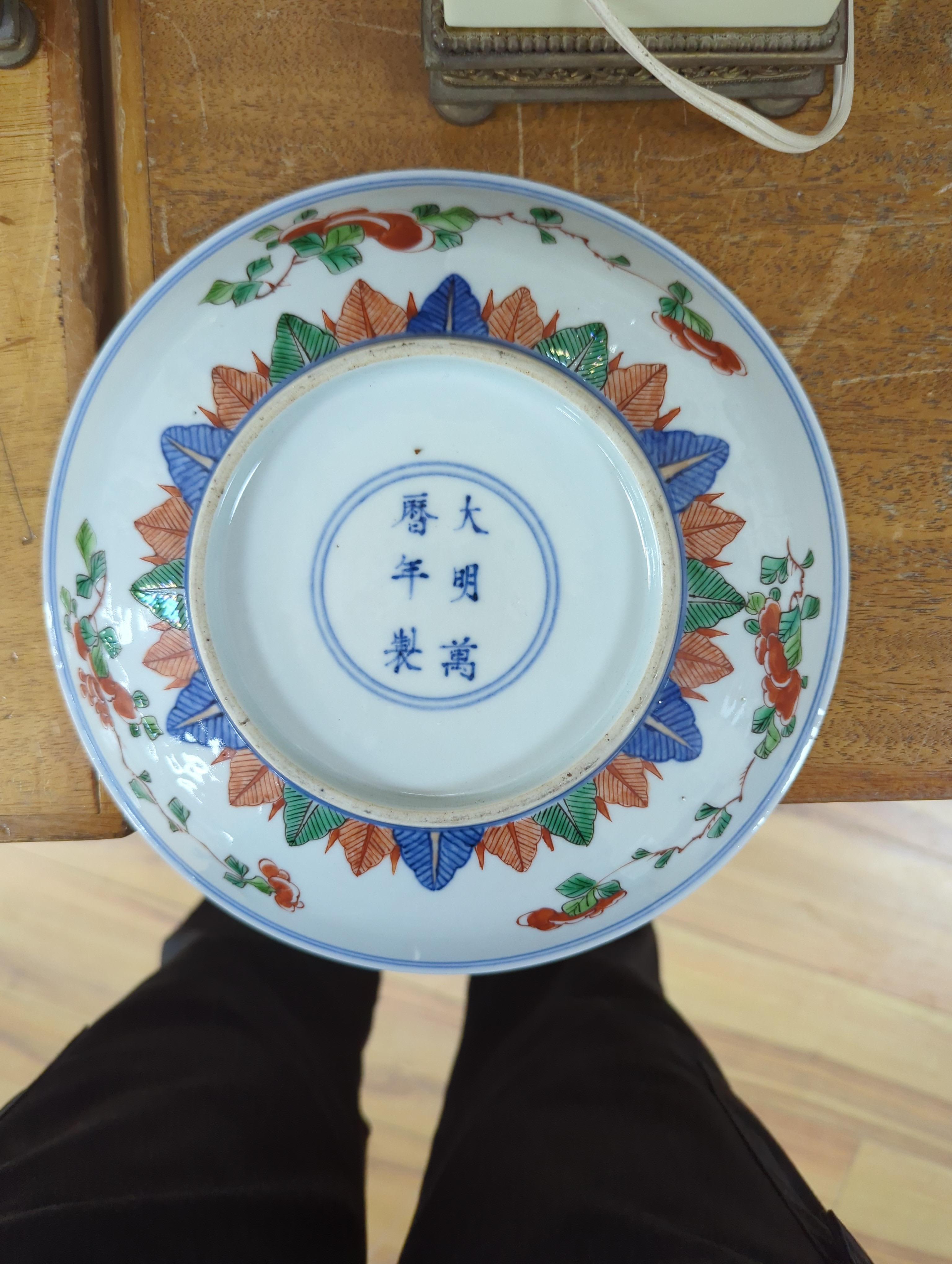 An 18th century Chinese famille rose bowl and a group of five Chinese wucai plates, each decorated with fruit, the bowl 23cm in diameter